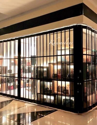 Exhibición sin límites y estética premium. La cortina transparente de cristal de Khamyluxe eleva el diseño de cualquier fachada comercial. Fabricada como una elegante cortina con paneles de cristal y opciones de cortina de cristal templado, esta cortina de cristal es la solución perfecta para escaparates y boutiques que exigen visibilidad 24/7 sin sacrificar el blindaje.