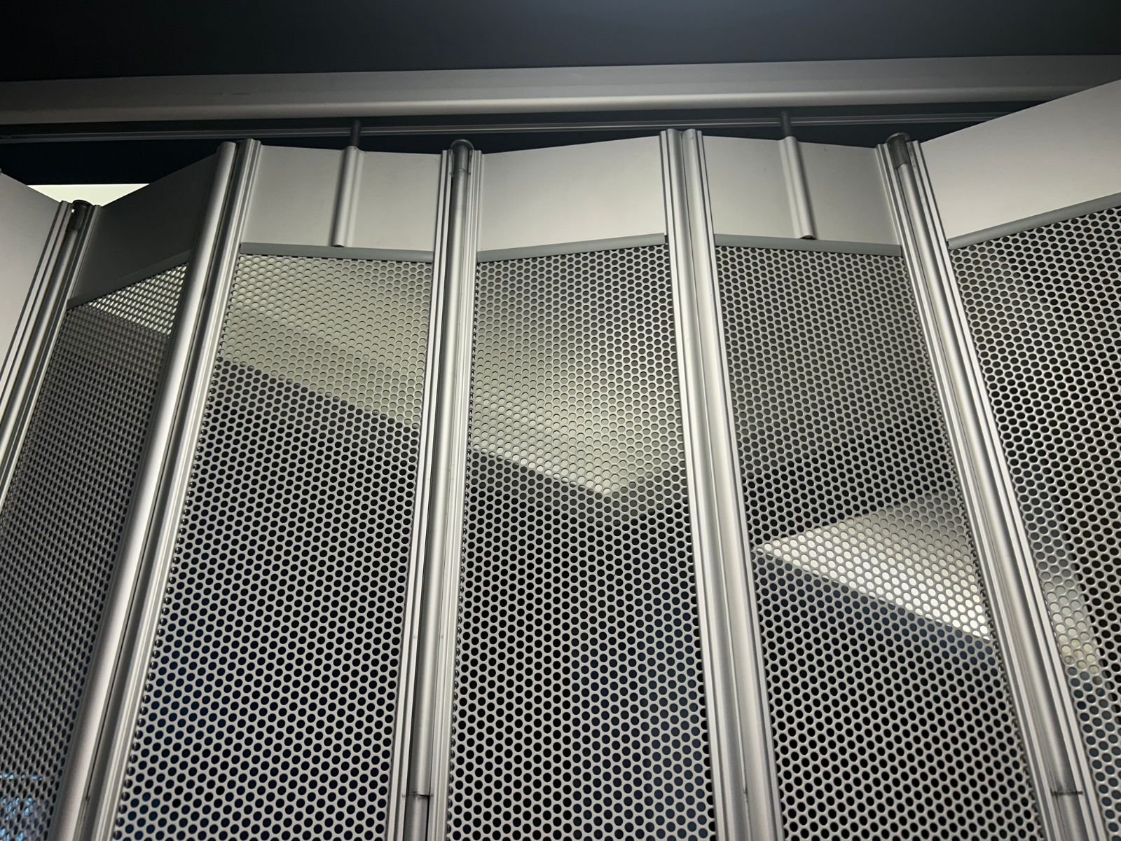 Detalle superior de riel y carretillas para cortina plegable de aluminio.