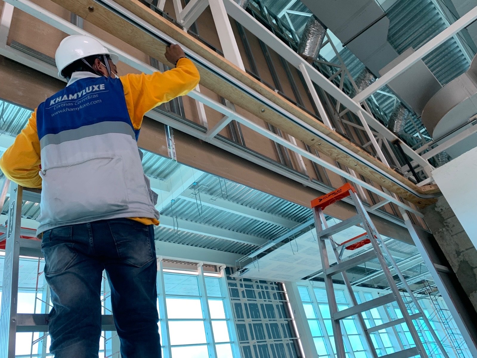 Un técnico instalando nuestras cortinas corredizas plegables en un centro comercial.